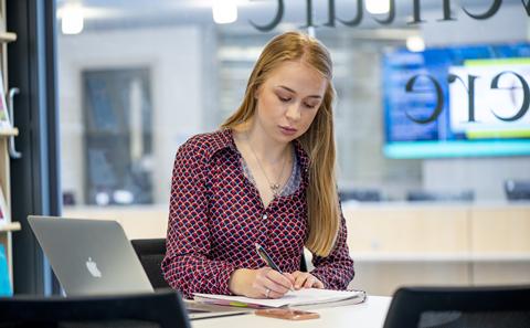 Student writing at table