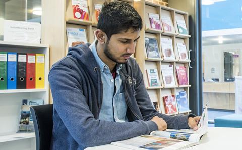 Student sat at table looking through book