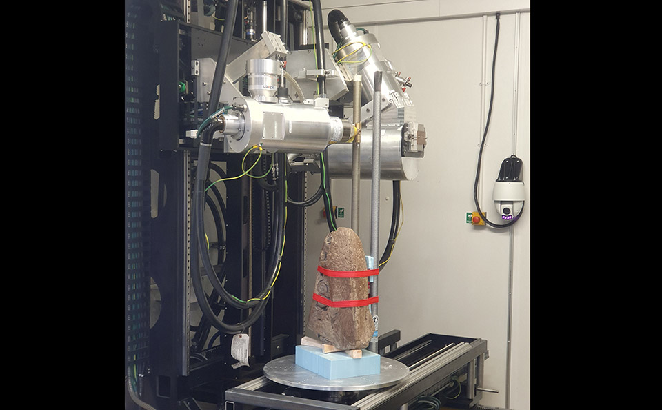 Fossil strapped to a metal pole with a chrome scanning arm positioned above.