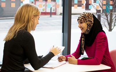 Two people talking at a desk