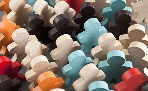 A group of different coloured wooden figures coming together as a community.