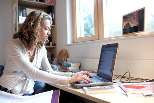 A female student leaning over a laptop computer.