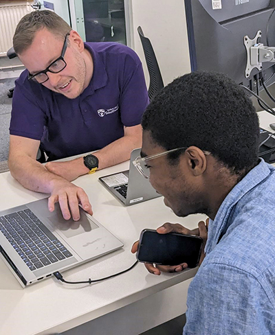 One of the Tech Hub staff wearing a purple hoodie, sat at their workstation