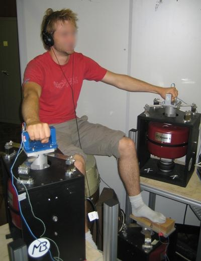 Participant using hand and foot controls connected to electrodynamic shakers for vibration perception and human response testing