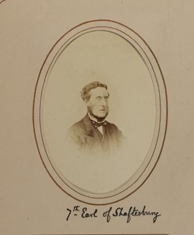 A sepia-toned oval photographic portrait is mounted on a cream card with a double-line oval border. Handwritten text beneath the portrait reads “7th Earl of Shaftesbury.”