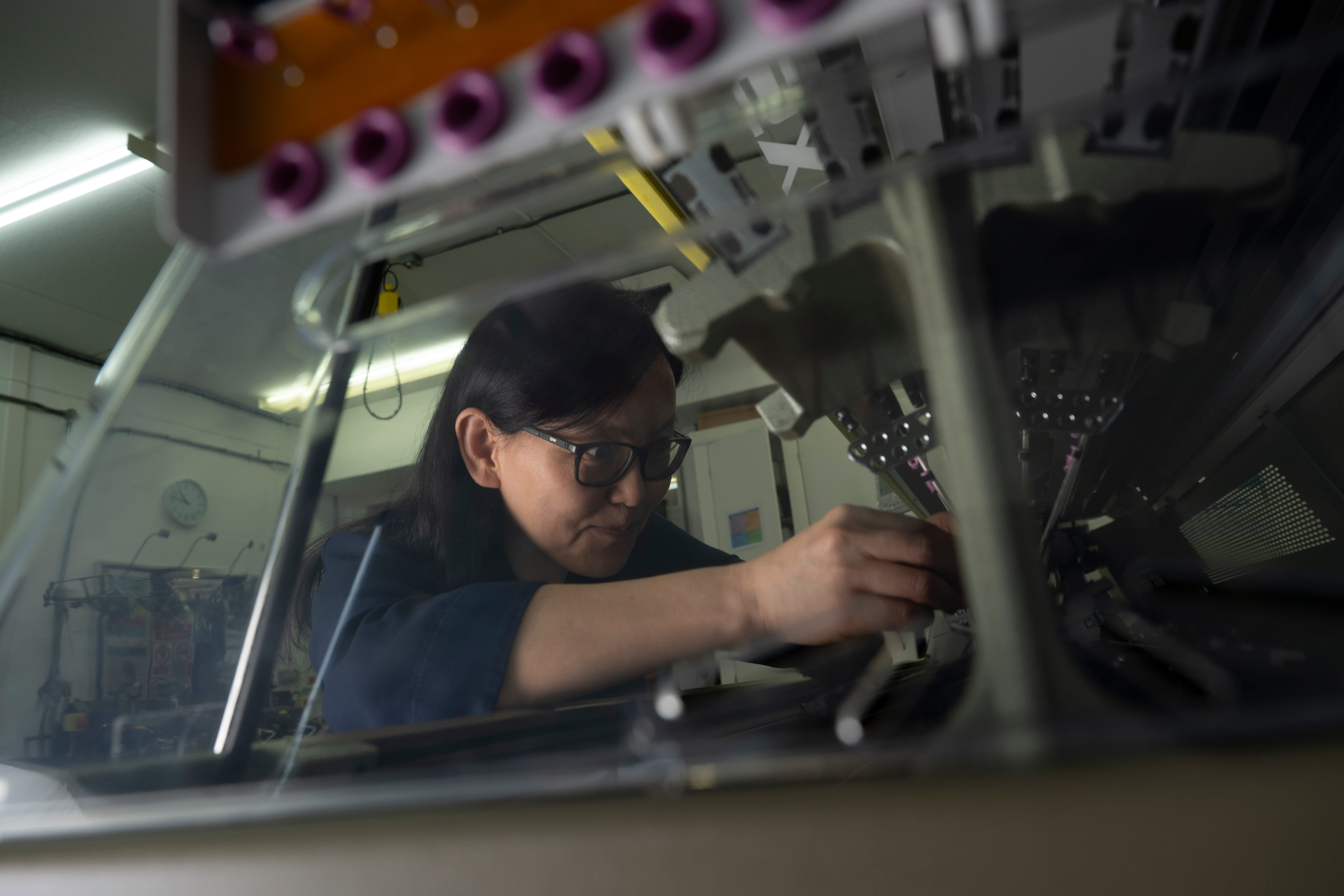 Professor Kai Yang adjusts equipment used in e-textiles research within a laboratory setting.