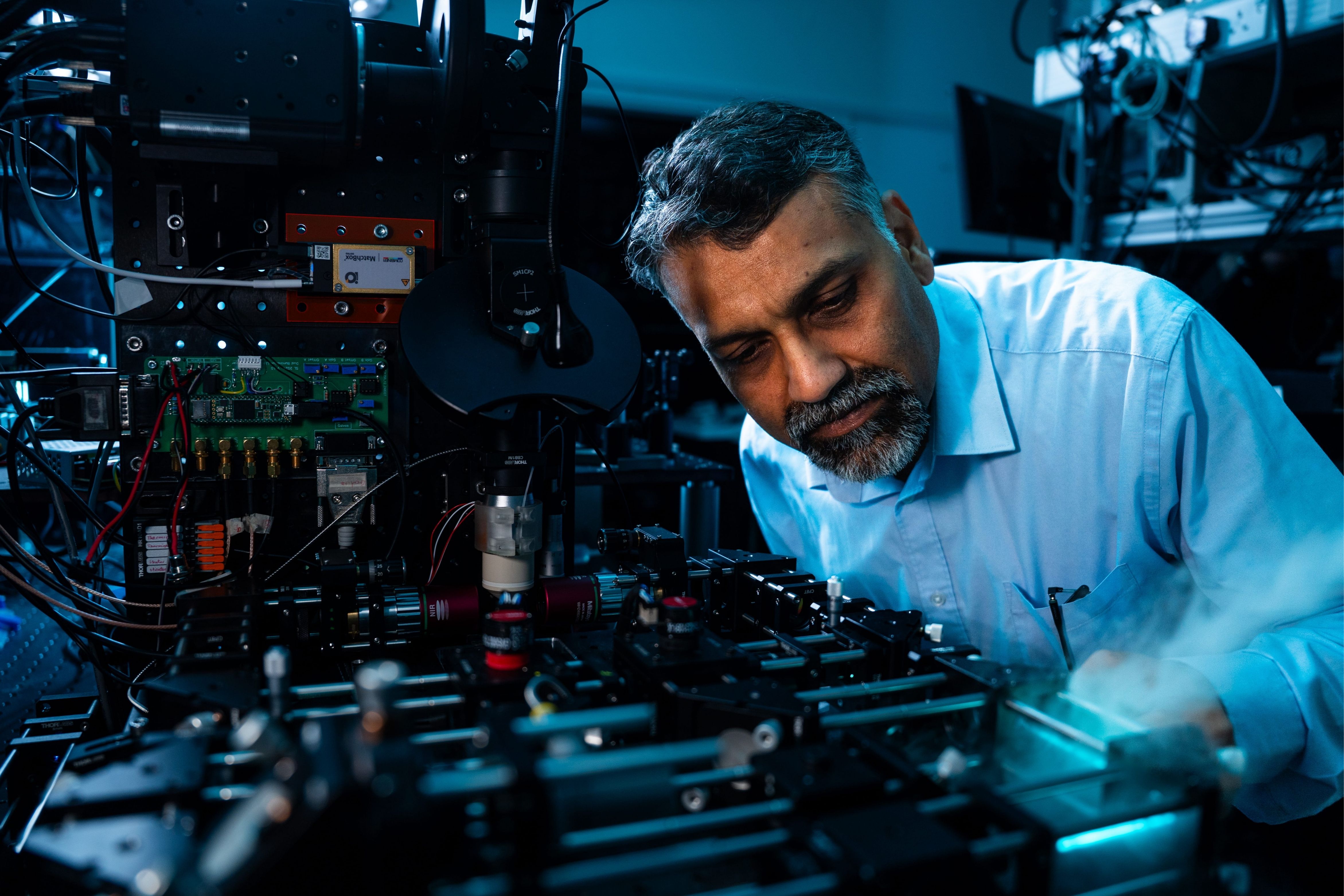 Researcher adjusting advanced laser and optical equipment during an experiment in a scientific laboratory.