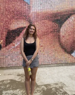 Alice standing infront of the World Begins With Every Kiss wall in Barcelona.