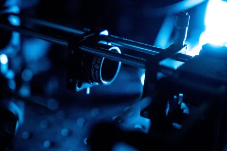Close-up of optical instrumentation with mounted components and blue illumination in a research lab.