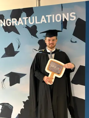 MSc Maritime Archaeology graduate Alex standing in his gown and mortar board posing for his graduation picture.