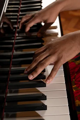 Hands playing the keys of a grand piano.