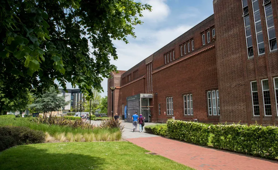 Exterior shot of academic building, trees and grass on a sunny day.