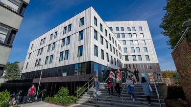 Students outside modern campus building on a sunny day.
