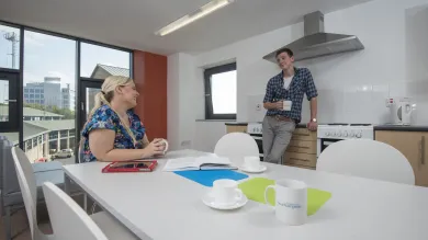 Two students relax and talk in a large communal kitchen.