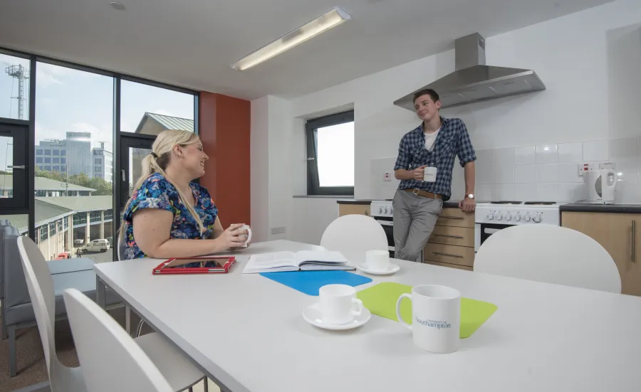 Two students relax and talk in a large communal kitchen.