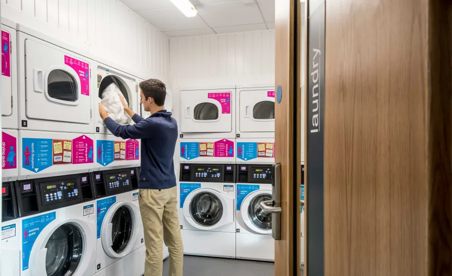 Student doing laundry in communal laundry room.