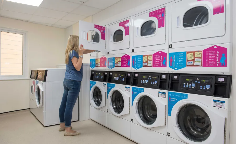 Student doing laundry in a communal laundry room.