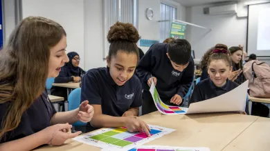 School pupils discussing classroom activity sheet