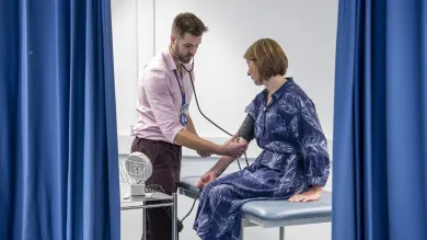 A medicine student examines a patient with a stethoscope in the clinical skills suite