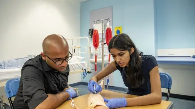 Medical students practice on a prosthetic arm in the clinical skills suite