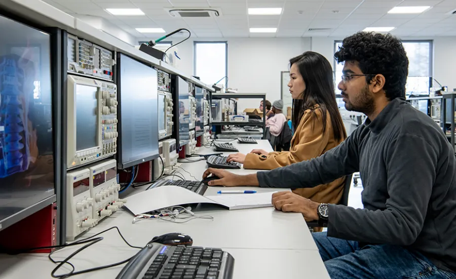 Two students working on computers at a work bench in the hardware projects laboratory.
