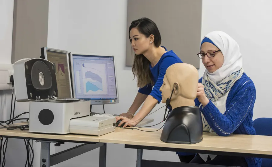2 students conducting a hearing test on a dummy.