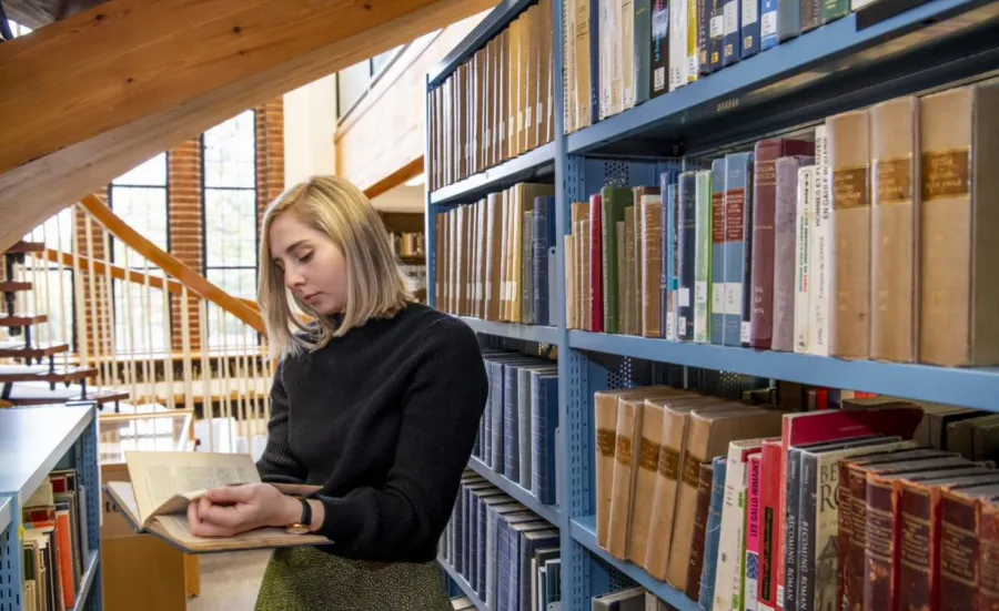 A student browsing by a bookshelf in Hartley Library