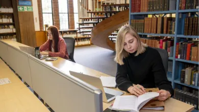 Students studying in Hartley Library with bookshelves in the background