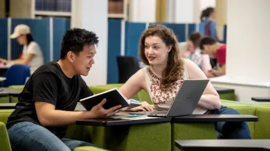 Two students collaborate on project work in a quiet learning space