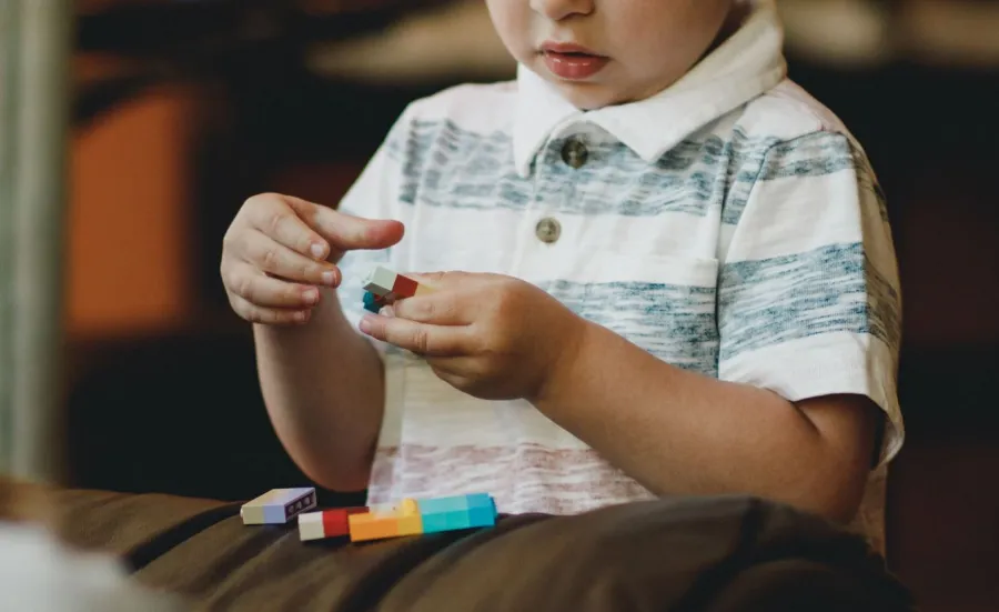 A child is absorbed in playing with brightly coloured building bricks