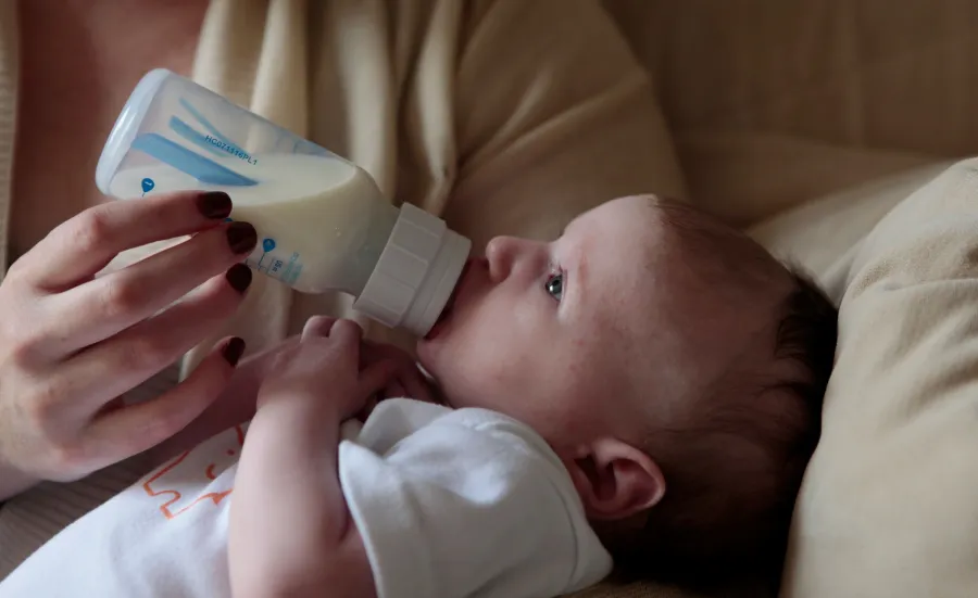 A mother feeds her baby from a bottle