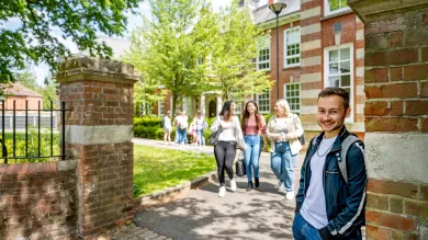 A student smiling at the gates of avenue campus