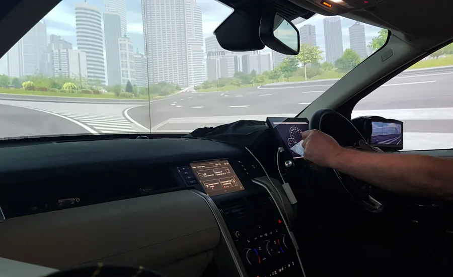 A student's arm on the steering wheel of a driving simulator