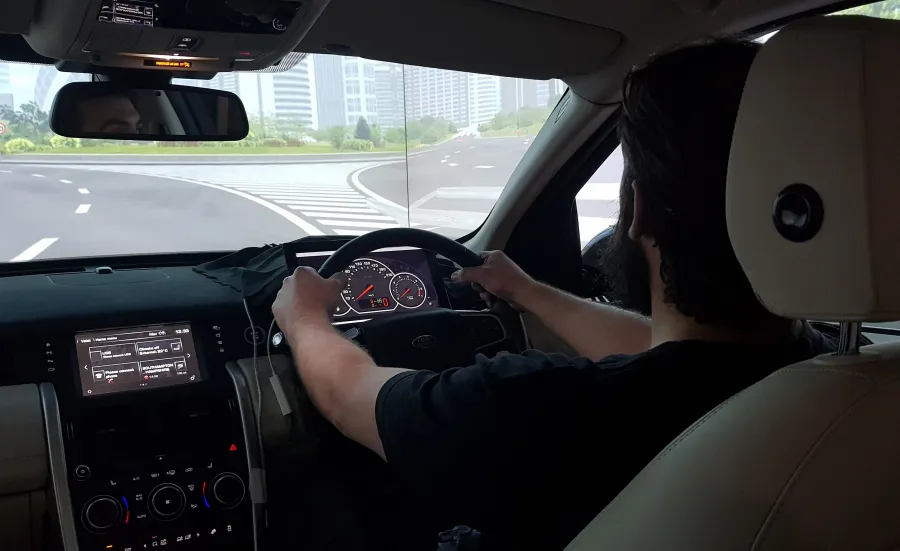 Student with both hands on the wheel of a driving simulator