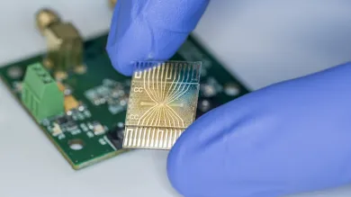 Two fingers wearing globes holding a microchip