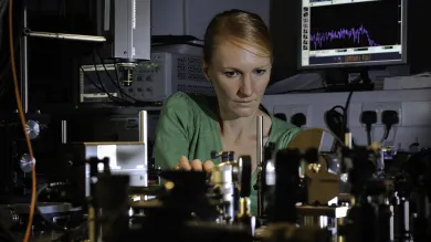 Professor Anna Peacock at work surrounded by equipment in the photonics lab