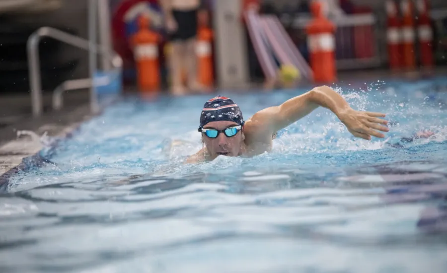 A swimmer in goggles and swimming cap powers towards us in a swimming pool