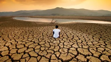 A man sit on dry land in an empty lake