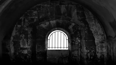 Dark prison cell with barred window