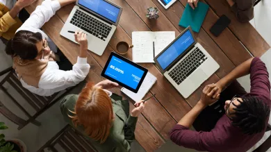 looking downwards at people sitting around a table with their laptops
