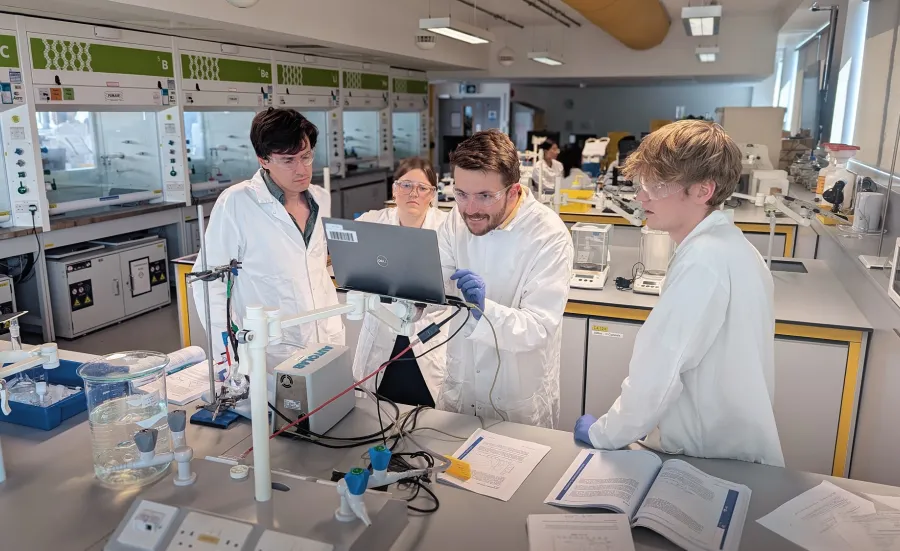 Several students in laboratory looking into the computer screen