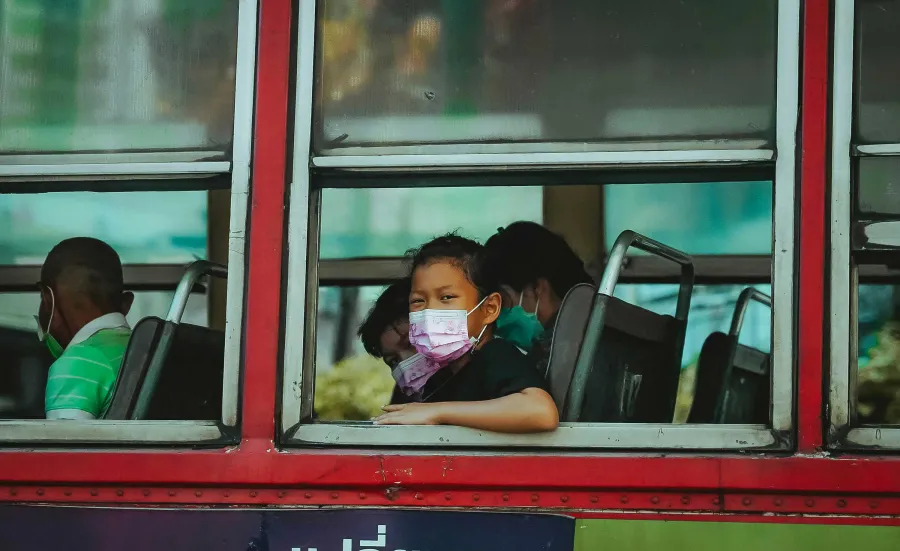 Girl with mask sitting inside bus