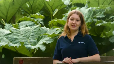 Student Adele, presents to camera from Valley Gardens on Highfield Campus. In the background large, green leaves are visible.