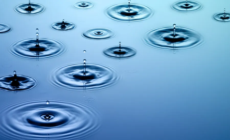 Droplets of water falling on water along with their concentric wave patterns