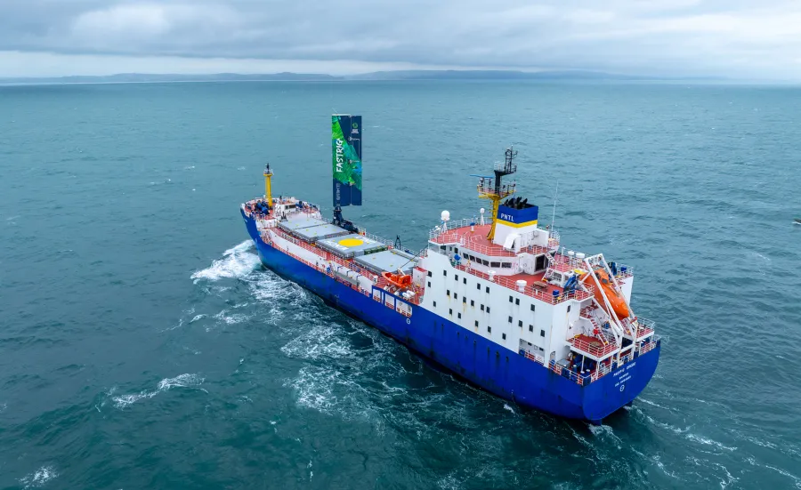 A large cargo vessel sailing on the ocean. It has a 20 metre-high wing sail. 