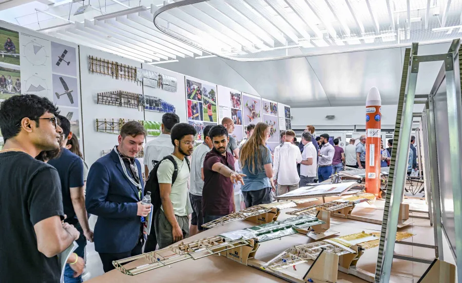 Visitors to the Engineering Design Show look at exhibits on benches. These are prototypes built by students and large printed information boards.