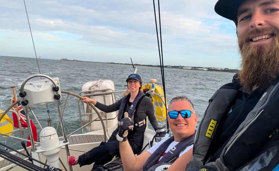 Participants on a sailing session out on the water smiling taking a selfie