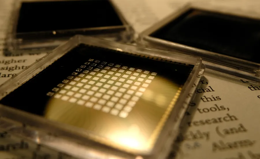three small square microchips placed on the pages of a book with visible text.