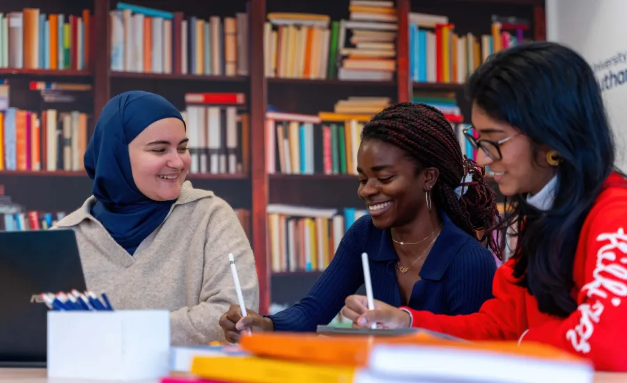 Students working together using digital tablets in a library-style setting.