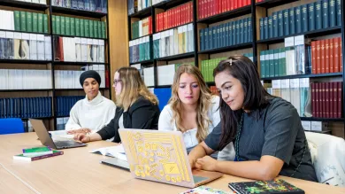 Students sat at table in library